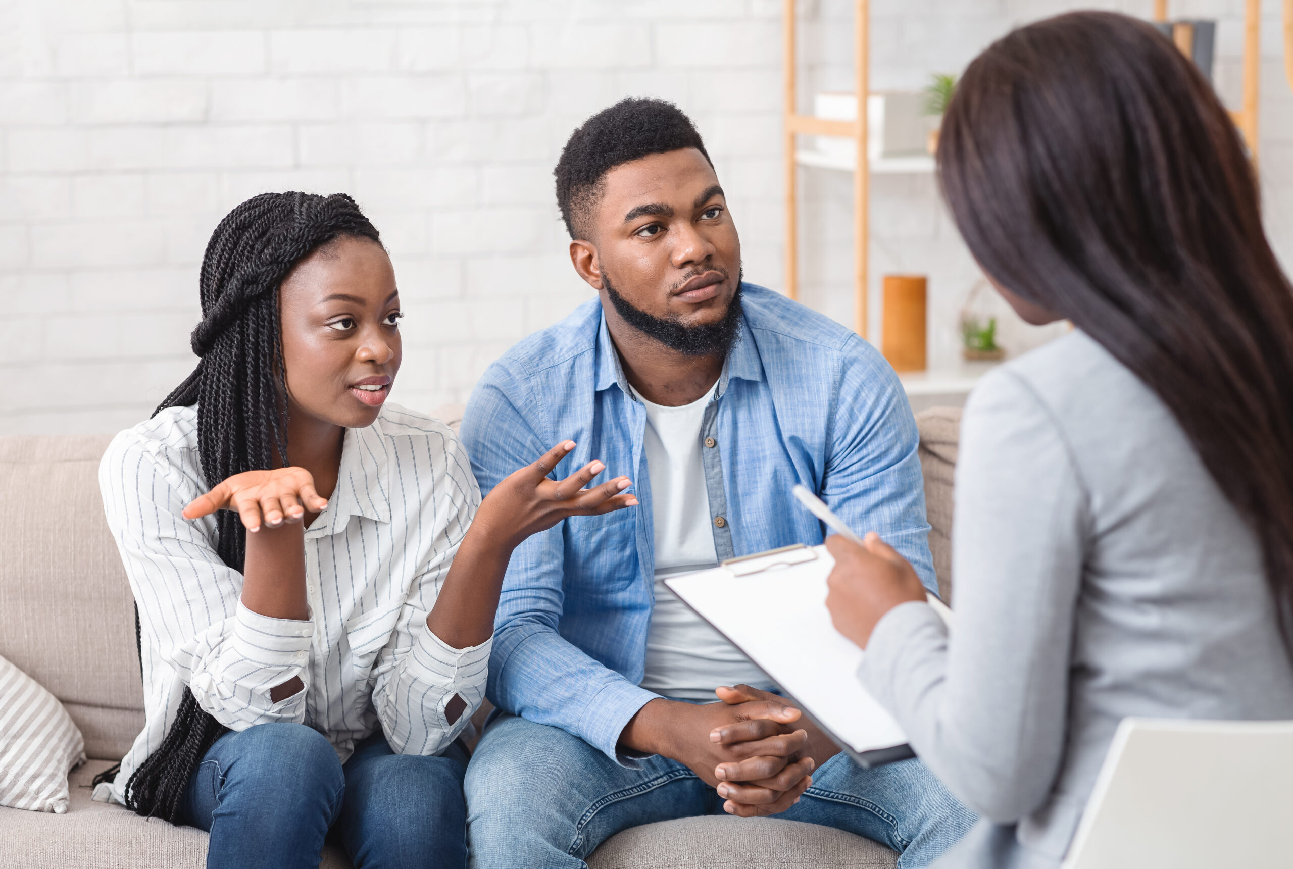 Marital psychotherapy concept. Young afro couple with relationship problems sitting at therapy session with psychologist